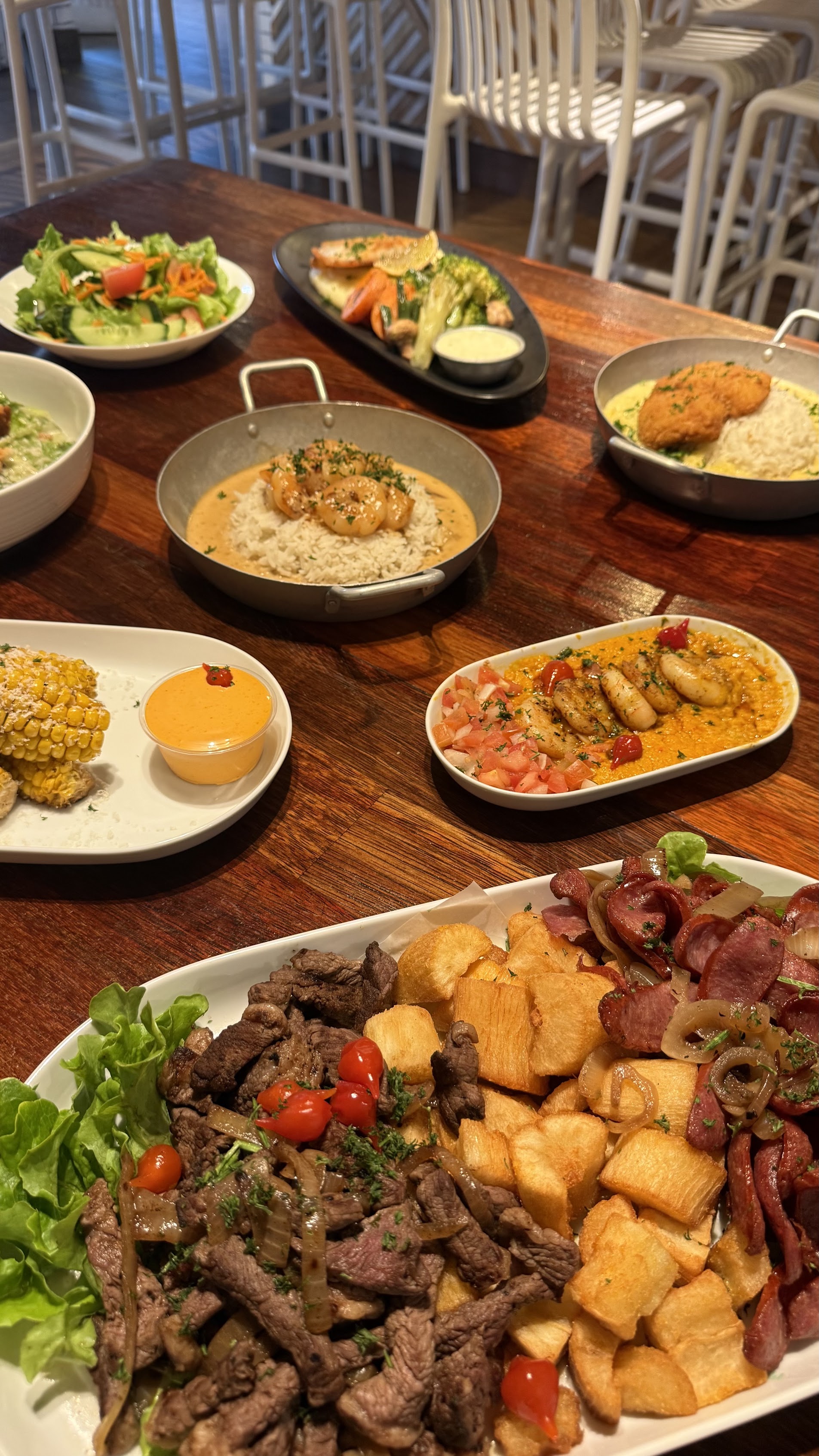 A spread of Casa Brasil dishes: prawns, garlic bread, picanha and cured meats